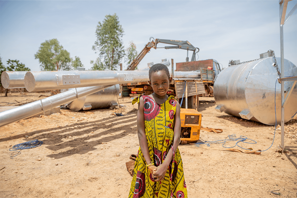 Egodine stands next to the drilling team working on digging a new borehole.