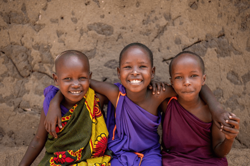 Naning’oi is wearing a purple dress. She is sitting between her step-sister, Betina (right), and her friend, Tamani (left).