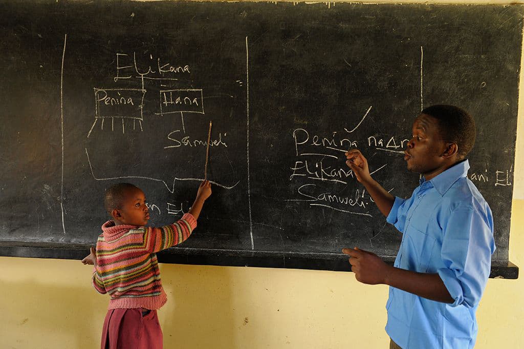 A teacher teaching a child in a classroom in Tanzania