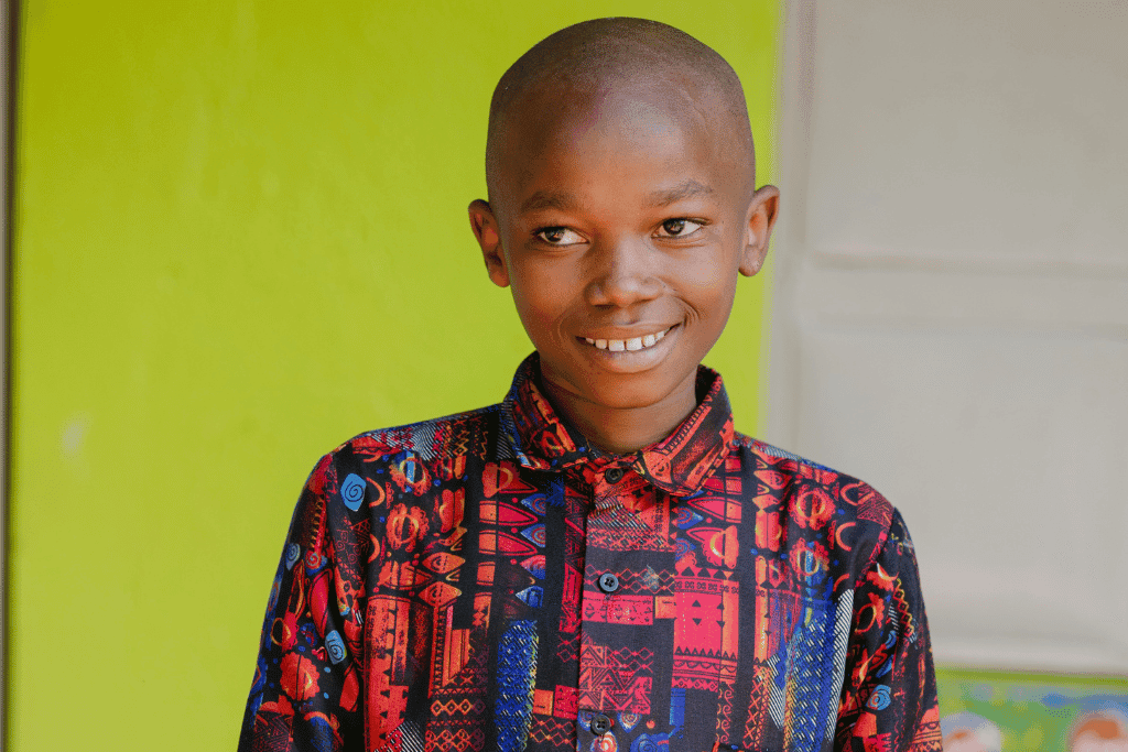Derek, 14, is a Compassion Participant. He is pictured here smiling in a red shirt.
