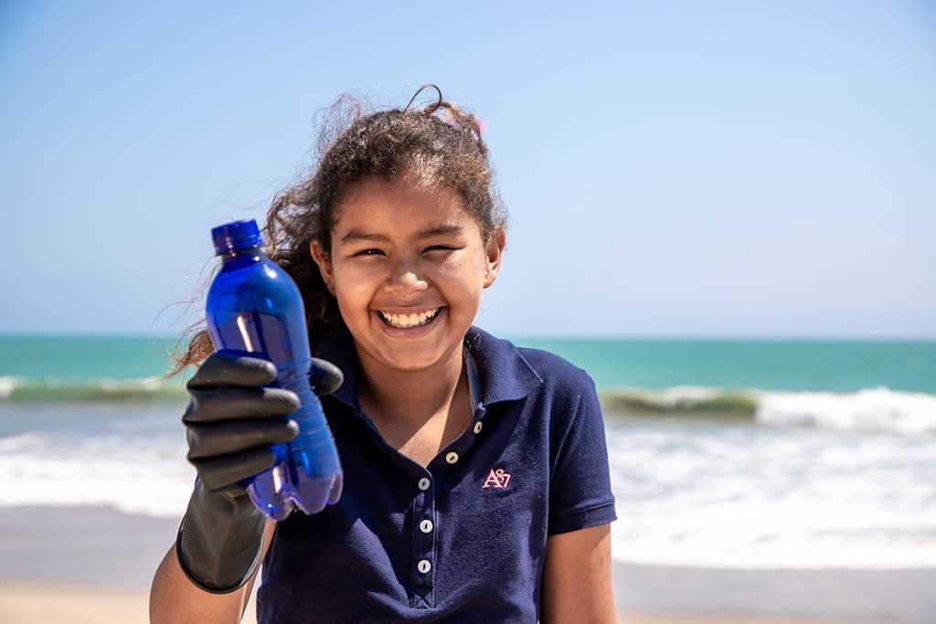 A girl holding out a plastic bottle