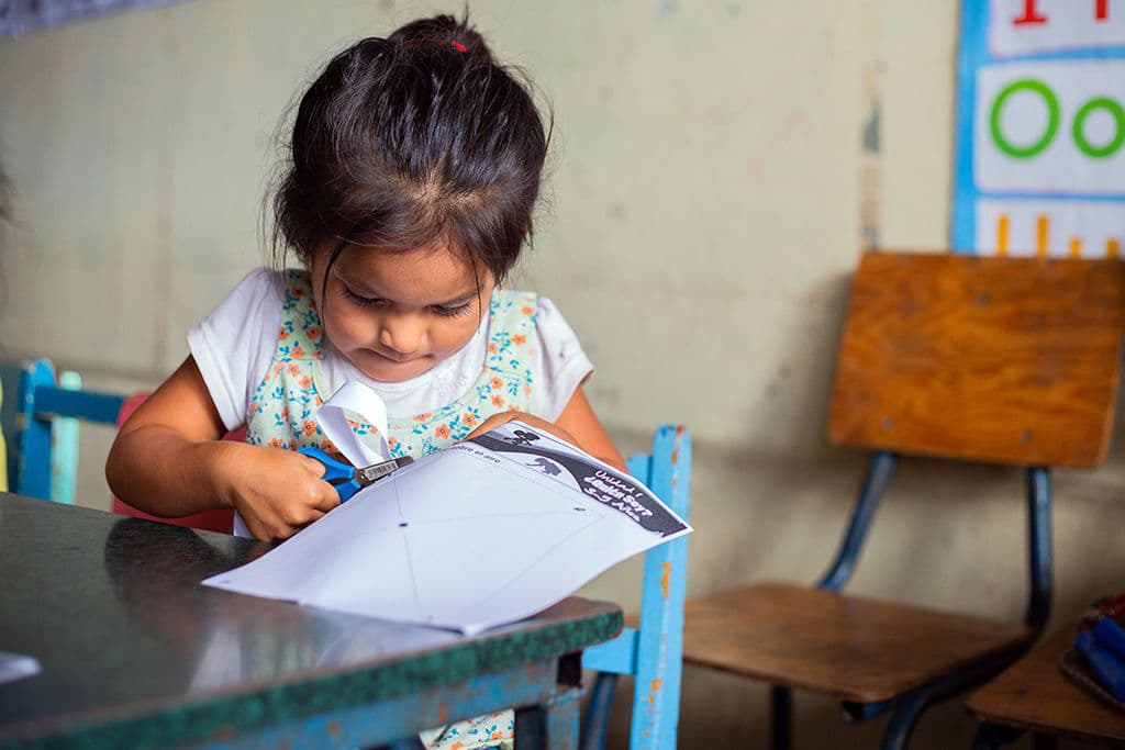 A young girl in a classroom in Honduras learns motor skills