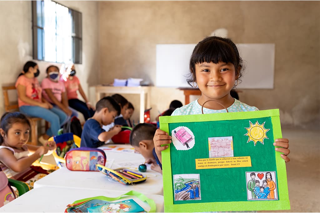 A girl holding up a display she made at her Compassion project