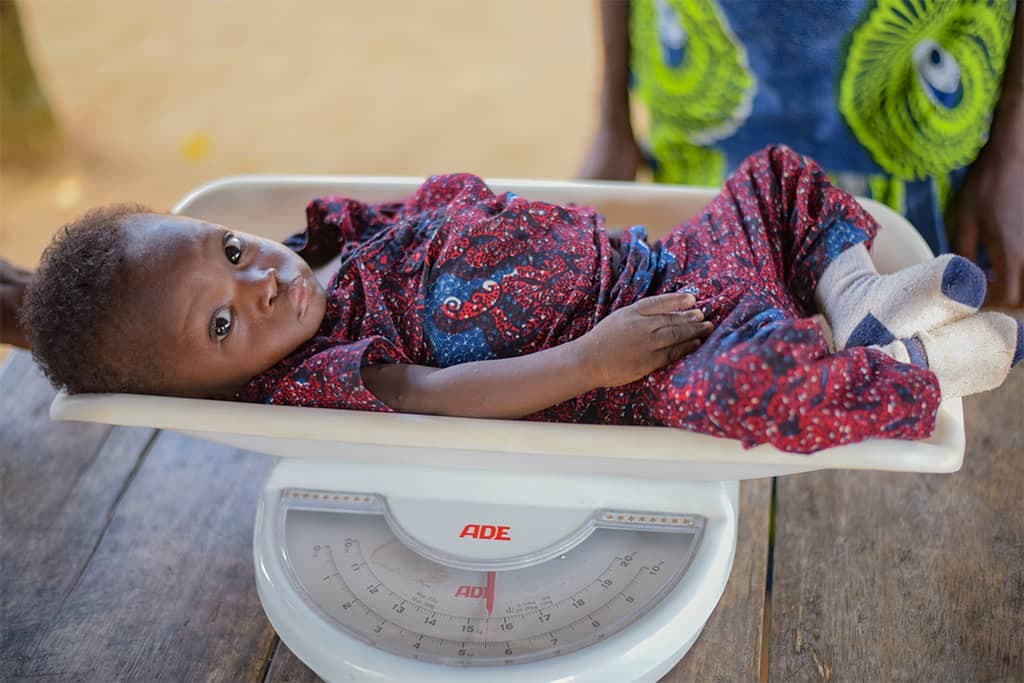 Akouvi's baby is being weighed on scales