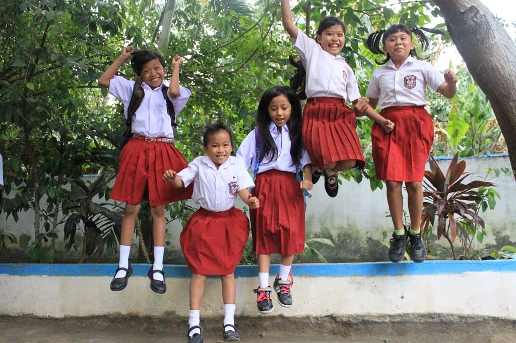 Girls jumping in Indonesia outside Compassion project