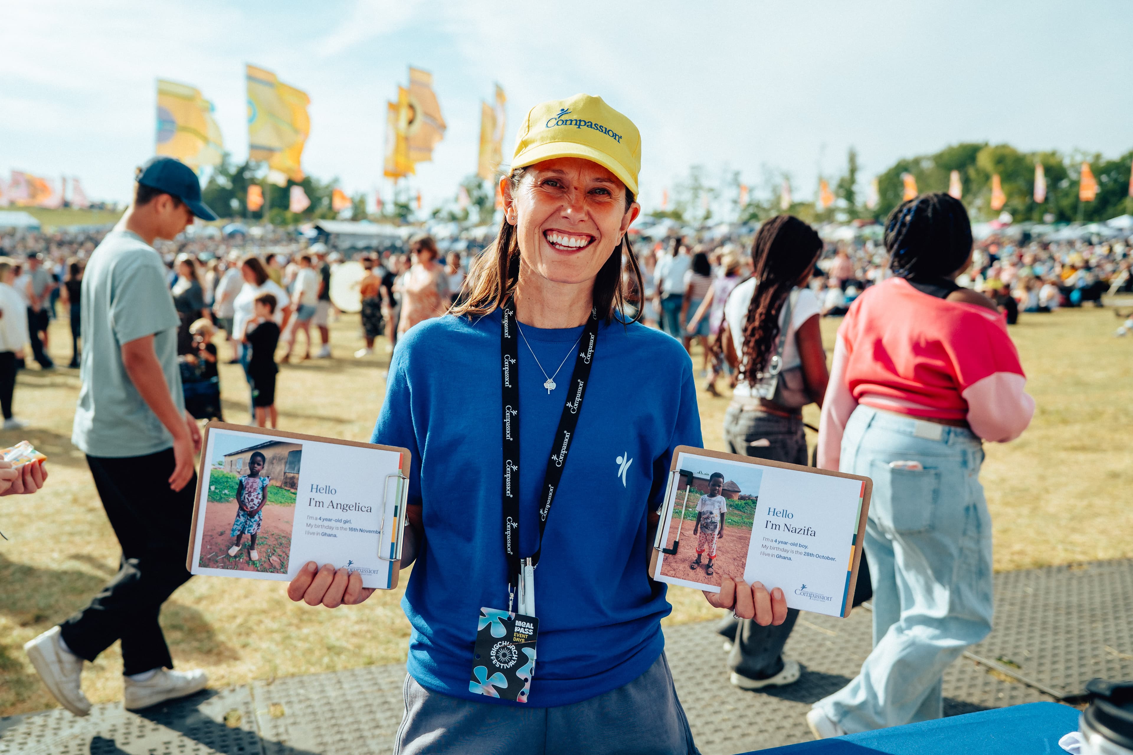 Woman at the festival in Compassion merchandise holding two children profiles