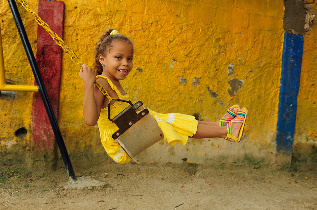 girl smiles on swing in yellow dress