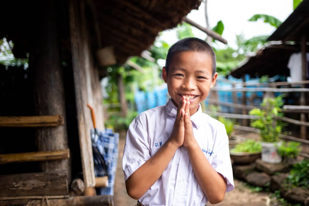 A boy put his hands together in a prayer pose in Thailand