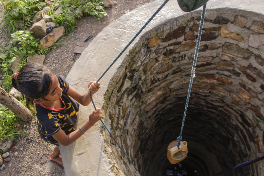 Yunita draws dirty water from a well