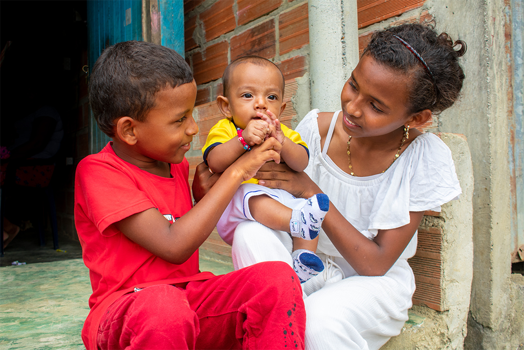 Ian and Saidith hold their baby brother, Deinner, outside their home in Colombia.