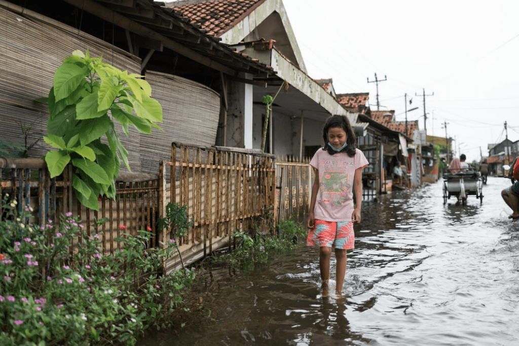 A girl walks down her street in ankle deep water.