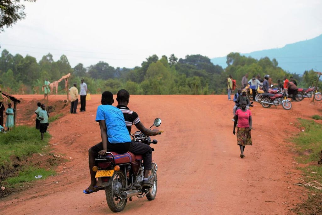 A boda boda driving someone home on a dusty Ugandan road