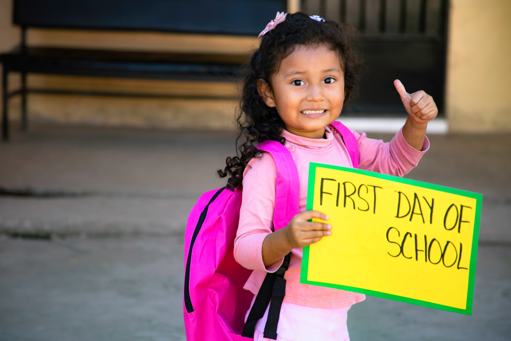 A girl holding the first day of school sign