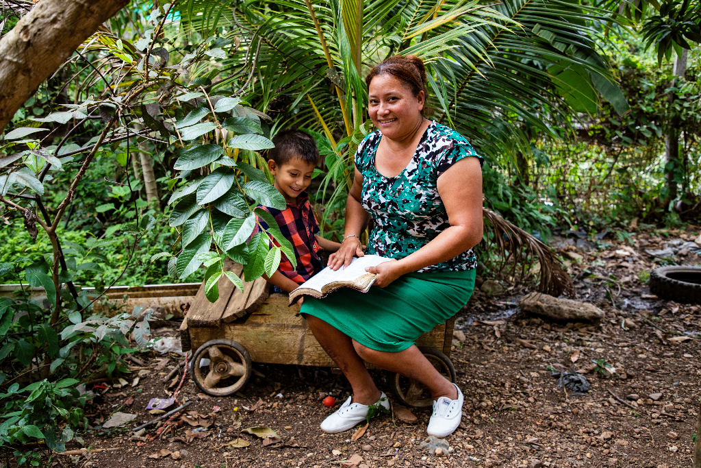 Obed and his mother are reading the Bible together outside.