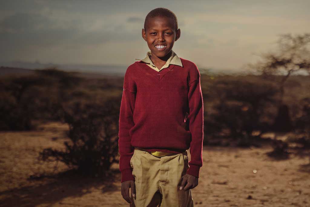 Elia, Kenya, stands outside as the sun sets
