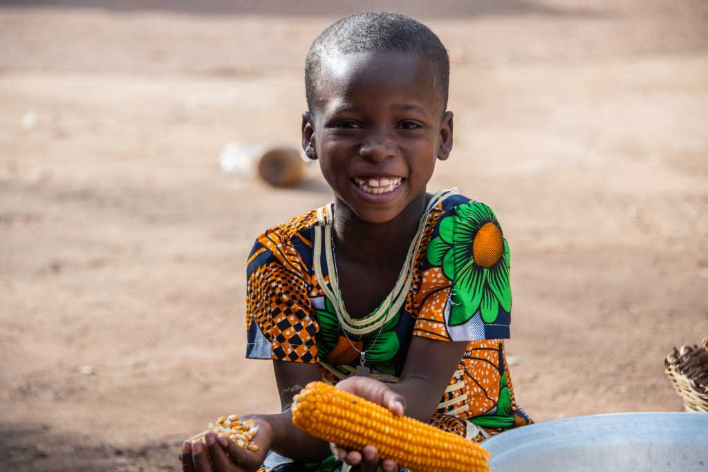 Ester, Togo, holds corn on the cob