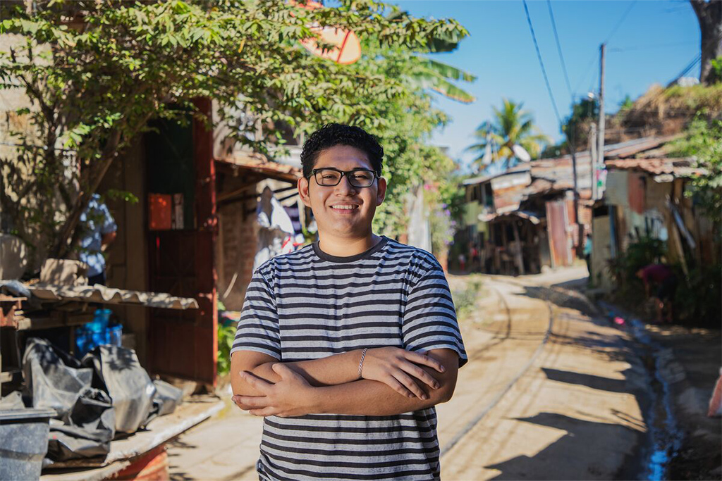 Twenty-two-year-old Kevin standing in his community. 