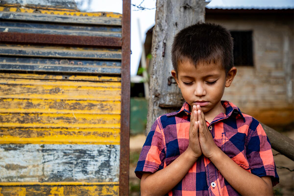 A boy praying outside his home in Honduras