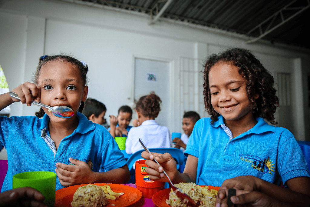 Two girls are eating a meal at Compassion Colombia.
